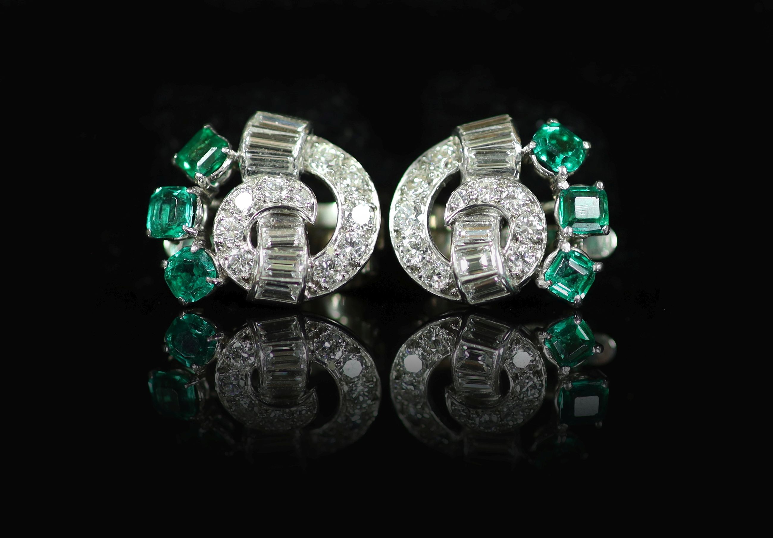A pair of 1950's white gold, emerald and diamond cluster scroll ear clips